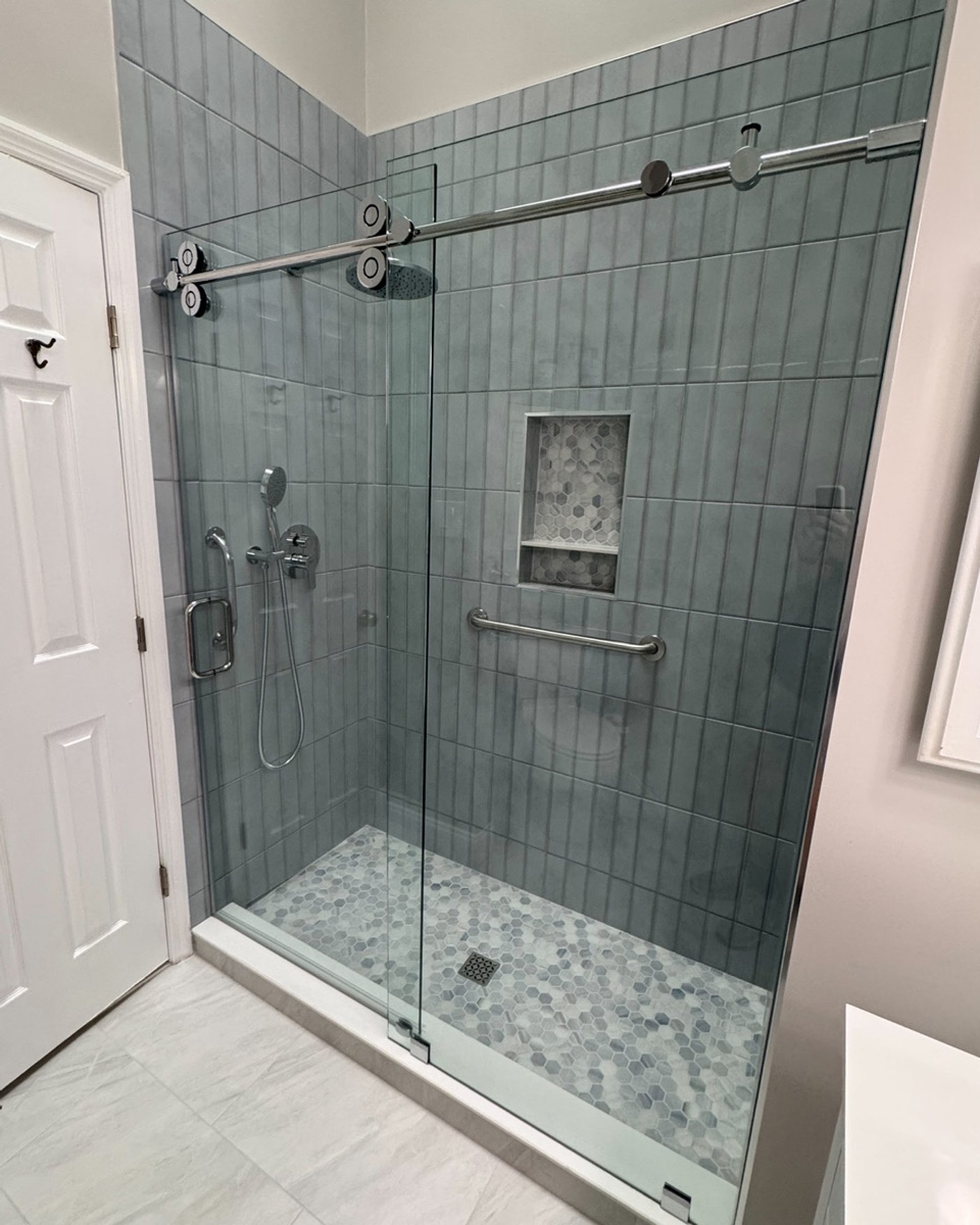 TideTrack Series barn-style single sliding glass shower door with fixed panel in a modern Maryland bathroom